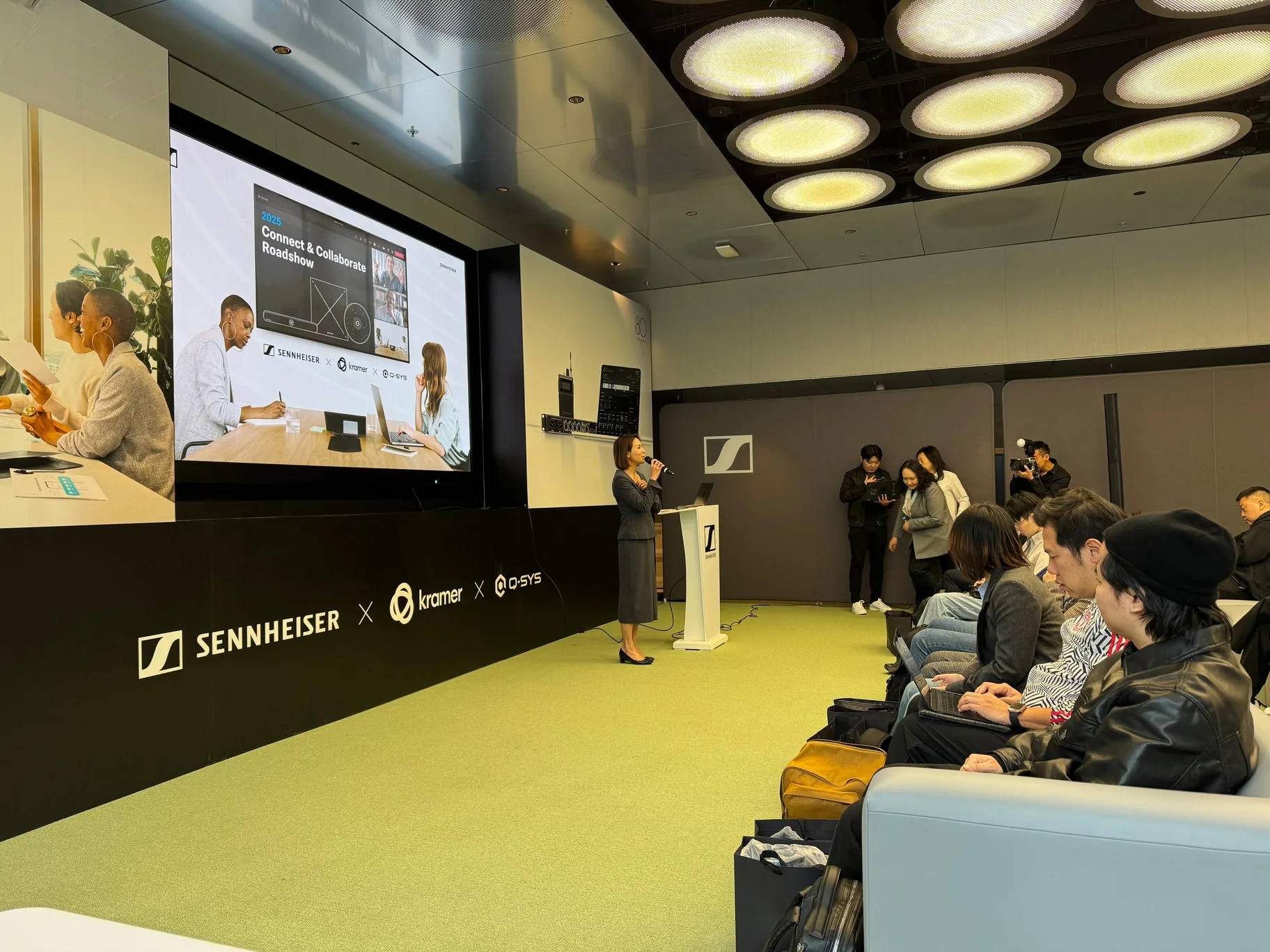A speaker addressing the seated audience at the Connect and Collaborate Roadshow