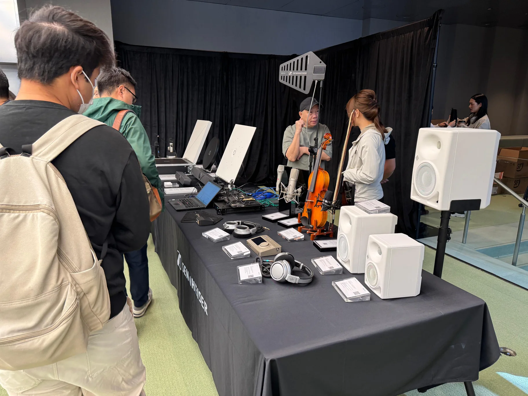 Visitors exploring microphones, headphones and speakers at the roadshow product demonstration table