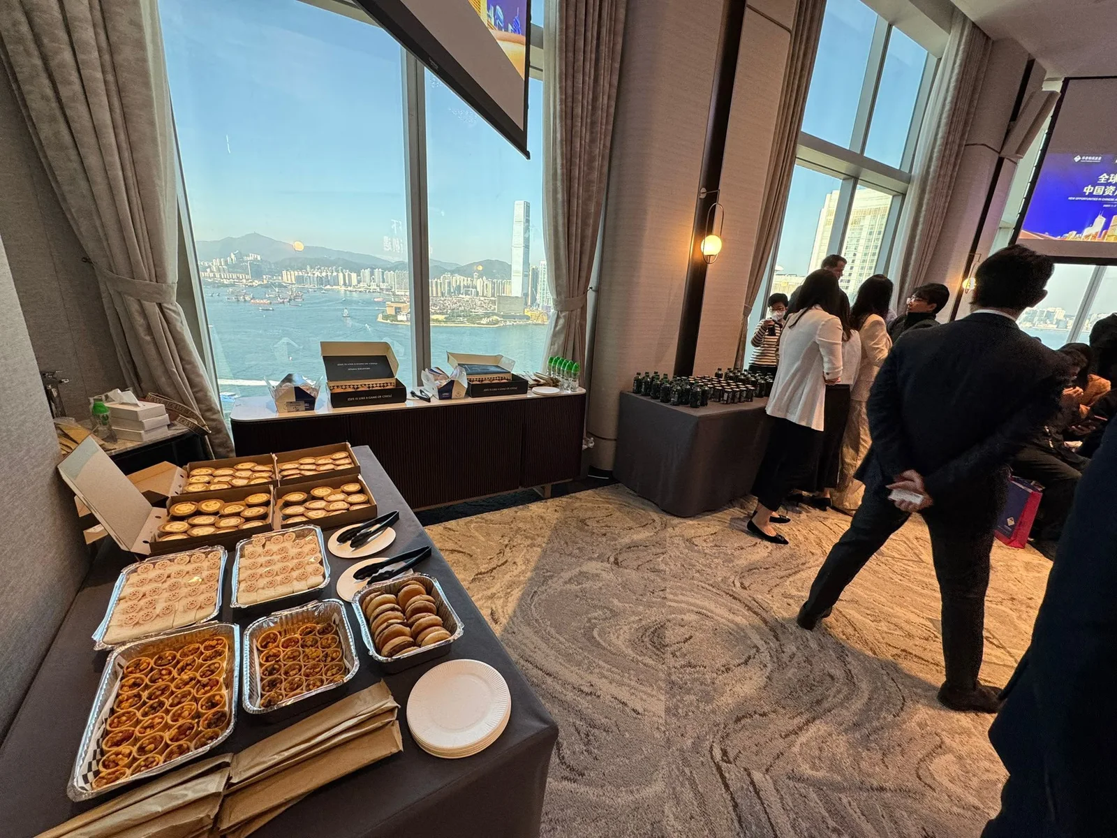 Guests gathering beside a refreshment table overlooking Victoria Harbour