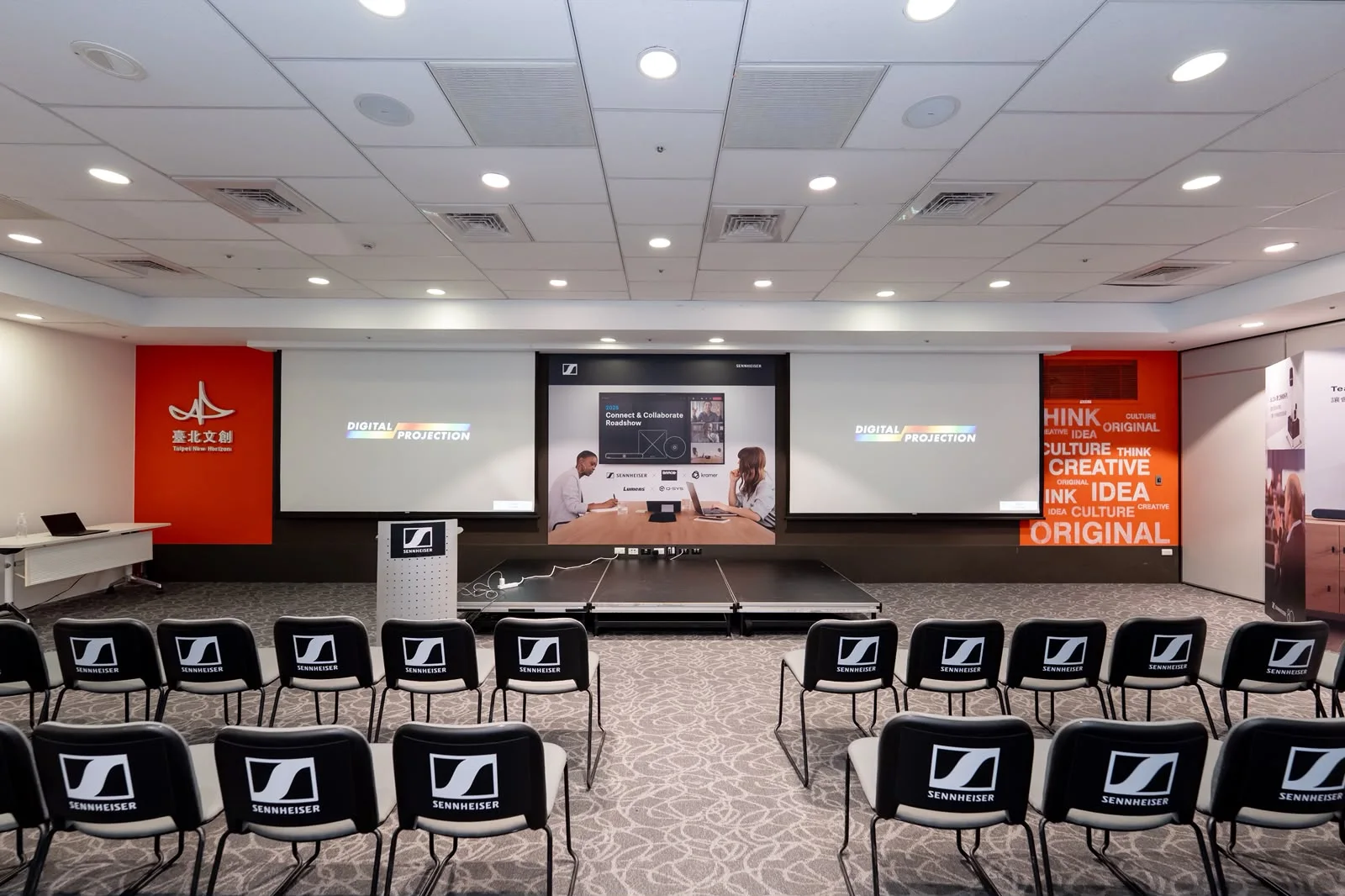 Sennheiser roadshow stage with two presentation screens, branded backdrop and guest seating